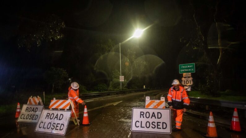 Trabajadores de la carretera cierran el acceso a la autopista 101 en Olive Mill Road como resultado del desbordamiento del arroyo San Ysidro debido a las fuertes lluvias en la zona el 9 de enero de 2023, en Montecito, California. (Apu Gomes/AFP vía Getty Images)