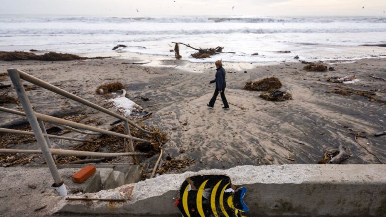 Una mujer camina por la playa de Río del Mar, cubierta de escombros de la tormenta, en Aptos, California, el 12 de enero de 2023. (Nic Coury/AFP vía Getty Images)