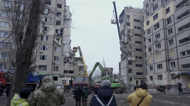 Residentes locales observan a los rescatistas que trabajan en un edificio residencial destruido tras el impacto de un misil, en Dnipro, el 16 de enero de 2023, en medio de la invasión rusa de Ucrania.   (VITALII MATOKHA/AFP vía Getty Images)