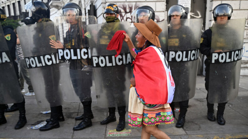 Una mujer indígena camina frente a la policía antidisturbios durante una protesta que exige la dimisión de la presidenta de Perú, Dina Boluarte, en Lima, el 23 de enero de 2023. (Ernesto Benavides/AFP vía Getty Images)