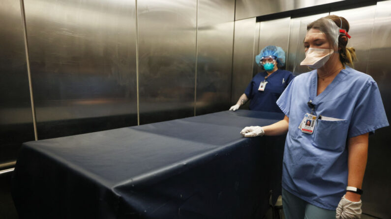 La técnica de la UCI Rae Harris (I) y la auxiliar de enfermería Kylee Samuelson transportan el cuerpo de un paciente fallecido por COVID-19 el 14 de diciembre de 2020 en La Mesa, California. (Mario Tama/Getty Images)