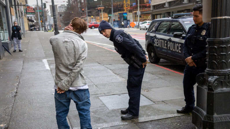 Oficiales de policía revisan a un hombre que dijo haber estado fumando fentanilo en el centro de Seattle el 14 de marzo de 2022 en Seattle, Washington. (John Moore/Getty Images)
