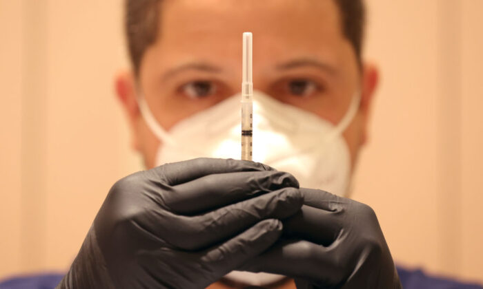 Un hombre llena jeringas con inyecciones de una dosis de refuerzo de una vacuna, en una clínica de vacunación contra el COVID-19, en San Rafael, California, el 6 de abril de 2022. (Justin Sullivan/Getty Images)