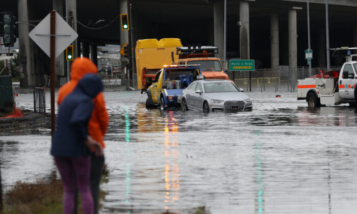 Algunas personas observan cómo una grúa saca un automóvil de una intersección inundada en Mill Valley, California, el 4 de enero de 2023. (Justin Sullivan/Getty Images)