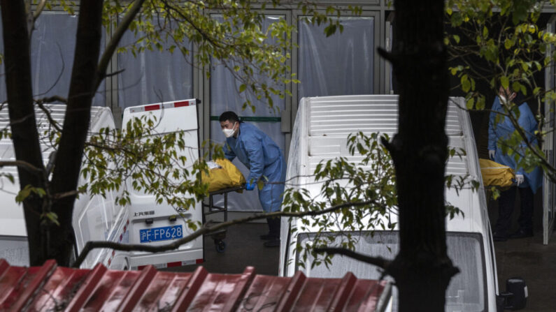 Trabajadores funerarios cargan cuerpos en furgonetas para llevarlos a incinerar en una concurrida funeraria local en Shanghái el 13 de enero de 2023. (Kevin Frayer/Getty Images)
