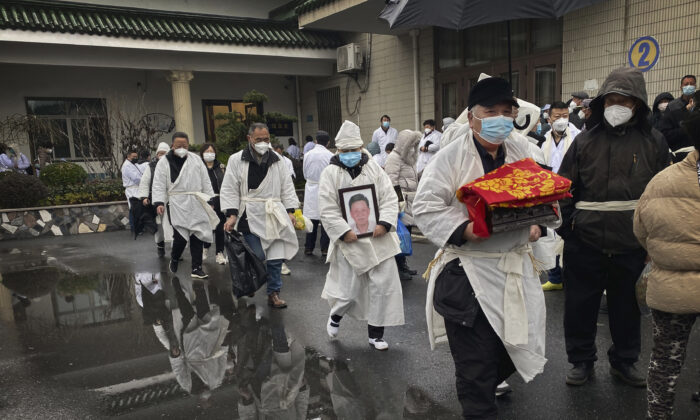 Un doliente lleva los restos incinerados de un ser querido mientras él y otras personas visten ropa tradicional blanca para funerales, durante un funeral en Shanghai, en una foto de archivo. (Kevin Frayer/Getty Images)

