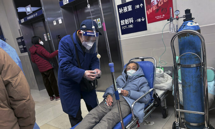 Un hombre usa un protector facial mientras ayuda a un ser querido en una camilla, en el pasillo de un hospital concurrido, en Shanghai, China, el 14 de enero de 2023. (Kevin Frayer/Getty Images)