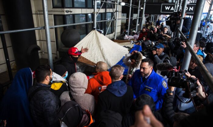 Inmigrantes ilegales hablan con miembros de NYC Homeless Outreach (Asistencia para personas sin hogar) mientras acampan frente al Hotel Watson tras ser desalojados el 30 de enero de 2023. (Michael M. Santiago/Getty Images)
