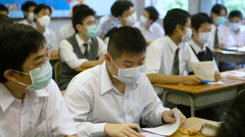Alumnos de secundaria asisten a clase con mascarillas en una escuela de Hong Kong el 22 de abril del 2003. (Peter Parks/AFP vía Getty Images)