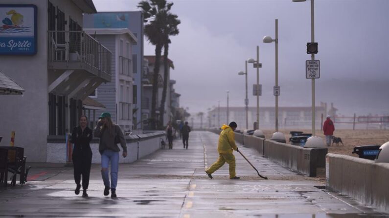 Vista de un trabajador despejando una vía de agua y arena durante una tormenta de lluvia en una playa de Los Ángeles, en una fotografía de archivo. EFE/Allison Dinner
