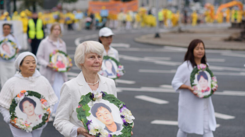 Los practicantes de Falun Dafa llevan fotografías de las víctimas de la persecución en China durante una marcha por el centro de Varsovia, en Polonia, el 9 de septiembre de 2022. (Mihut Savu/The Epoch Times)
