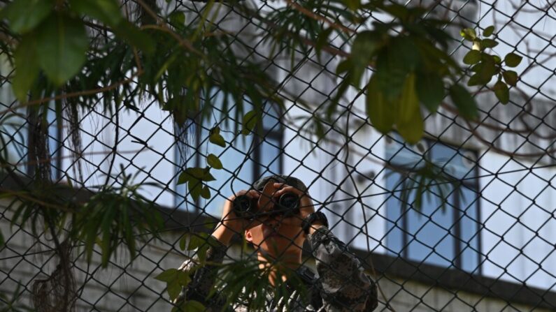 Un soldado del Ejército Popular de Liberación (EPL) chino utiliza binoculares junto a la valla perimetral del cuartel PLA Hong Kong Garrison el 17 de noviembre de 2019. (PHILIP FONG/AFP vía Getty Images)
