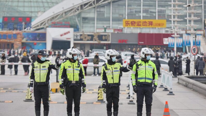 Policías montan guardia mientras los residentes hacen fila para someterse a la prueba contra el COVID-19 en Nantong, en la provincia costera oriental china de Jiangsu, el 15 de febrero de 2022. (STR/AFP vía Getty Images)
