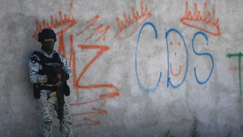 Un soldado mexicano monta guardia junto a unos grafitis del narcotraficante Mayo Zambada (MZ) y del grupo criminal "Cártel de Sinaloa" (CDS), en el poblado Palmas Altas, municipio de Jerez de García Salinas, estado de Zacatecas, México, el 14 de marzo de 2022. (PEDRO PARDO/AFP vía Getty Images)