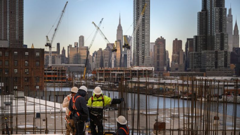 Una vista general muestra a los trabajadores de la construcción de pie ante el horizonte de Manhattan y el Empire State Building, en Brooklyn el 24 de enero de 2023. (Ed Jones/AFP a través de Getty Images)