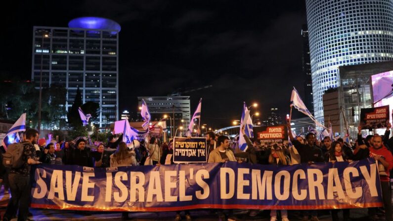 Israelíes marchan con una pancarta durante una manifestación contra los controvertidos planes del gobierno de dar a los legisladores más control sobre el sistema judicial, Tel Aviv (Israel), 4 de febrero de 2023. (Jack Guez/AFP vía Getty Images)
