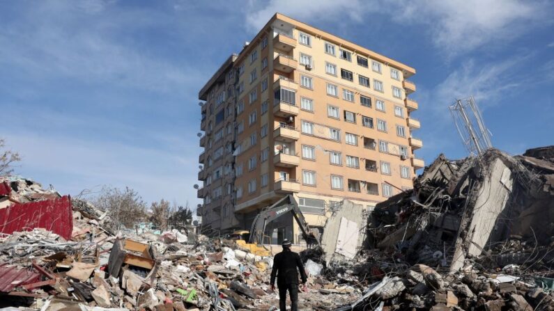 Un hombre camina entre los escombros de un edificio derrumbado hacia un edificio aún en pie s en Kahramanmaras, cerca del epicentro del terremoto, el día después de un terremoto de magnitud 7,8 sacudió el sureste del país, el 7 de febrero de 2023.(ADEM ALTAN/AFP via Getty Images)