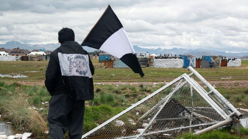 Un hombre con una bandera peruana teñida de negro junto a la valla del aeropuerto donde se produjeron enfrentamientos con la policía peruana -dentro de las protestas contra la presidenta Dina Boluarte- el 9 de febrero de 2023, en Juliaca, región de Puno, Perú. (JUAN CARLOS CISNEROS/AFP vía Getty Images)