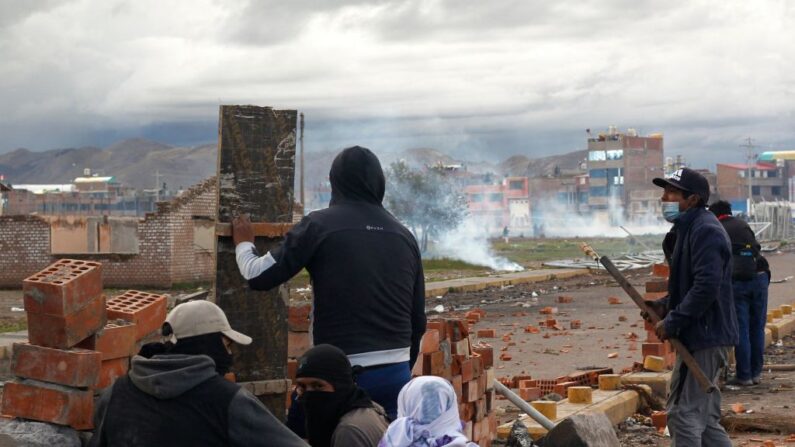 Manifestantes se cubren de gases lacrimógenos durante enfrentamientos con fuerzas policiales al cierre de una marcha en conmemoración de un mes de la muerte de 18 personas en recientes enfrentamientos, el 9 de febrero de 2023, en Juliaca, región Puno, Perú. (Juan Carlos Cisneros/AFP vía Getty Images)