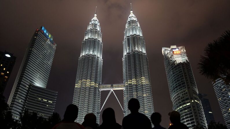 Un grupo de personas frente a las emblemáticas Torres Gemelas Petronas de Malasia en Kuala Lumpur el 19 de marzo de 2016. (Mohd Rasfan/AFP vía Getty Images)