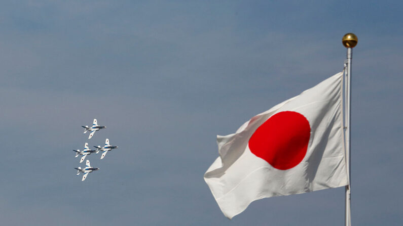Una bandera nacional japonesa ondea mientras aviones del equipo de vuelo acrobático de la Fuerza de Autodefensa Aérea de Japón, conocido como Blue Impulse, vuelan durante la revisión anual en el Campamento de Asaka de la Fuerza de Autodefensa Terrestre de Japón el 23 de octubre de 2016 en Asaka, Japón.  (Tomohiro Ohsumi/Getty Images)