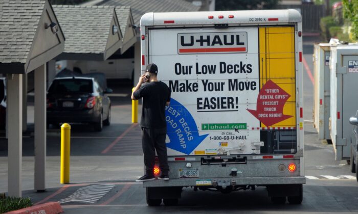 Un hombre habla por su teléfono móvil mientras viaja en la parte trasera de un camión de mudanzas en Pacifica, California, el 26 de enero de 2016. (Josh Edelson/AFP vía Getty Images)
