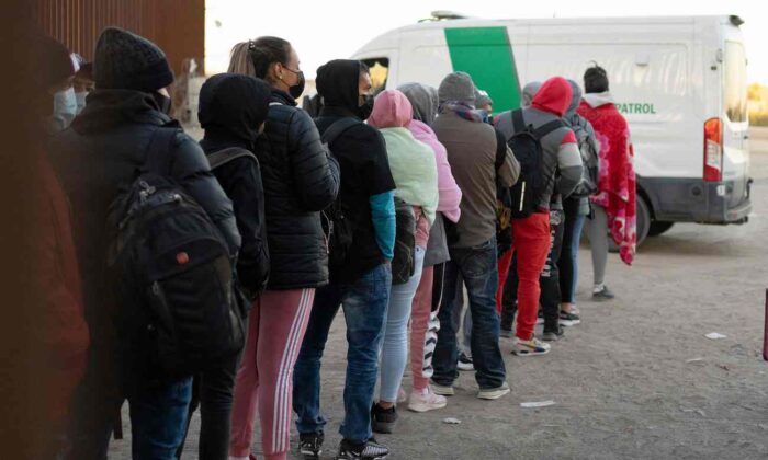 Extranjeros ilegales que buscan asilo hacen fila para ser procesados ​​por agentes de la Patrulla de Aduanas y Protección Fronteriza de Estados Unidos en una brecha en la valla fronteriza entre EE.UU. y México cerca de San Luis, Arizona, el 26 de diciembre de 2022. (Rebecca Noble/AFP vía Getty Images)