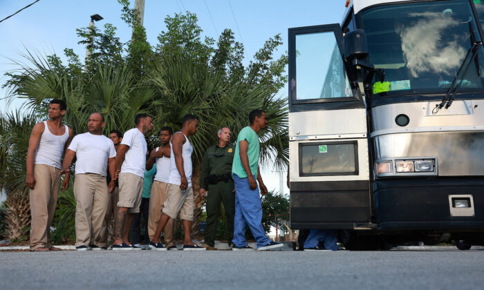 Inmigrantes ilegales procedentes de Cuba hacen cola para subir a un autobús y ser conducidos a una estación de Aduanas y Protección Fronteriza de EE. UU. mientras son procesados en Marathon, Florida, el 5 de enero de 2023. (Joe Raedle/Getty Images)