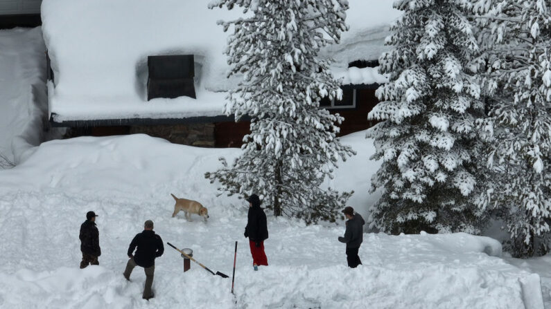 Los residentes de pie en el techo de una casa cubierta de nieve el 21 de marzo de 2023 en South Lake Tahoe, California. (Justin Sullivan/Getty Images)