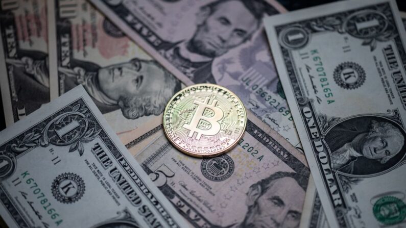 Esta fotografía tomada el 26 de abril de 2021 en París muestra una imitación física de la criptomoneda Bitcoin expuesta en billetes de dólares estadounidenses. (Martin Bureau / AFP vía Getty Images)