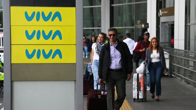 Varias personas pasan junto a una valla publicitaria de Viva Air a las afueras del aeropuerto internacional El Dorado, en Bogotá (Colombia), el 28 de febrero de 2023. (Juan Barreto/AFP vía Getty Images)