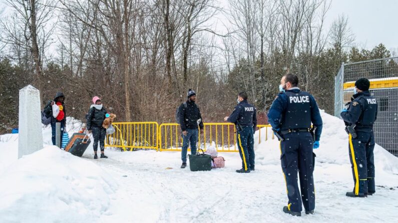 Los oficiales hablan con los migrantes cuando llegan al cruce fronterizo de Roxham Road en Roxham, Quebec, Canadá, el 2 de marzo de 2023. (Sebastien ST-Jean/AFP vía Getty Images)