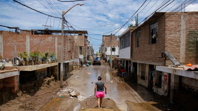 Un residente de La Esperanza, al norte de Trujillo en el departamento de La Libertad, Perú, camina por una calle inundada -también cubierta de lodo y arena- el 13 de marzo de 2023, tras las fuertes lluvias causadas por el ciclón Yaku. (ARTURO GUTARRA/AFP vía Getty Images)