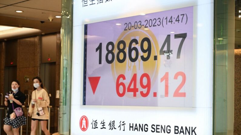 Un grupo de personas pasa junto a un cartel que muestra las cifras del índice Hang Seng en Hong Kong el 20 de marzo de 2023. (Peter Parks/AFP vía Getty Images)