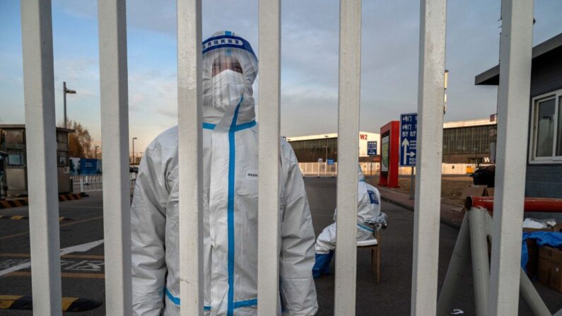 Un trabajador de control de epidemias llamados "Grandes blancos" es fotografiado usando EPP mientras vigila la puerta de una instalación de cuarentena del gobierno en Beijing, China, el 7 de diciembre de 2022. (Kevin Frayer/Getty Images)