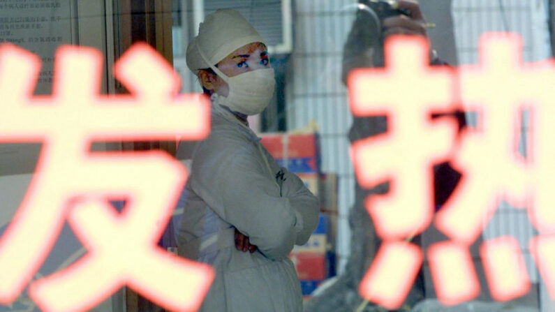 Una enfermera china descansa en el interior de una sala de cuarentena especial para pacientes con fiebre (palabra en primer plano) en el Hospital Popular nº 8 de Guangzhou, en la capital de la provincia de Guangdong (China), el 29 de diciembre de 2003. (STR/AFP vía Getty Images)