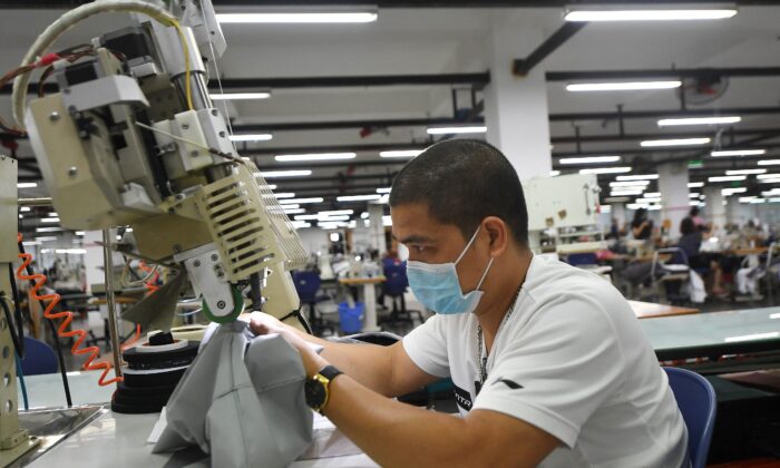 Un trabajador con una mascarilla facial mientras trabaja en la fábrica de Maxport, que fabrica ropa deportiva para varias marcas de ropa textil, en Hanoi, Vietnam, el 21 de septiembre de 2021. (Nhac Nguyen/AFP a través de Getty Images)