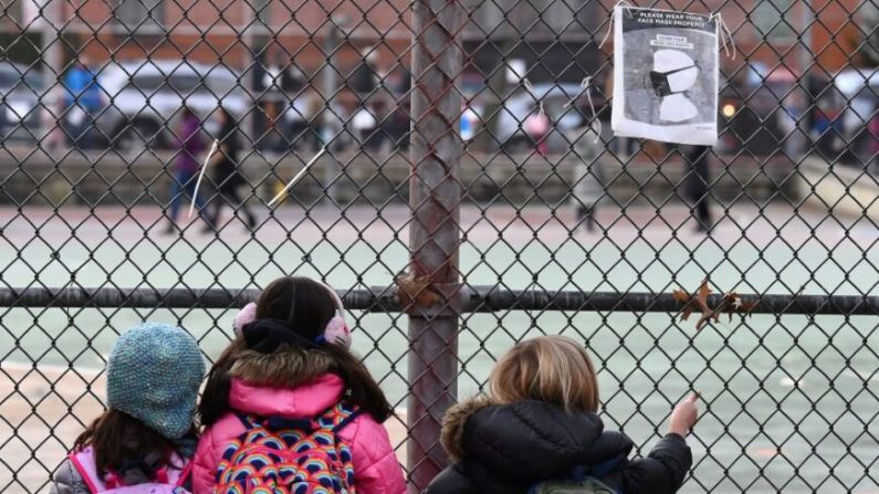 Unos niños observan el recinto de su colegio mientras esperan para ir a clase en el primer día de reapertura escolar en el barrio de Brooklyn, en Nueva York, el 7 de diciembre de 2020. (Angela Weiss/AFP vía Getty Images)