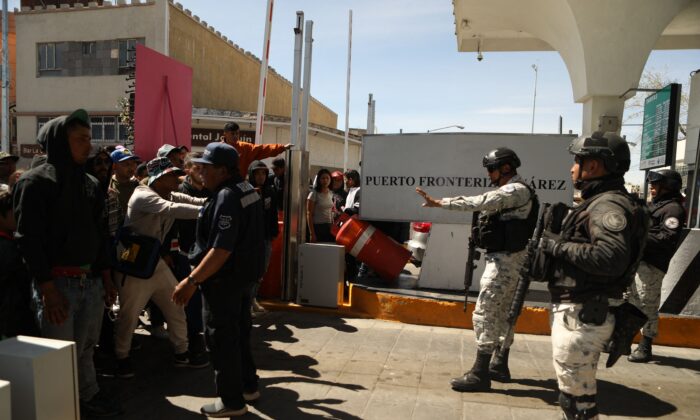 Inmigrantes ilegales, en su mayoría de origen venezolano, intentan cruzar por la fuerza a Estados Unidos en el Puente Internacional Paso del Norte en Ciudad Juárez, estado de Chihuahua, México, el 12 de marzo de 2023. (HERIKA MARTINEZ/AFP vía Getty Images)