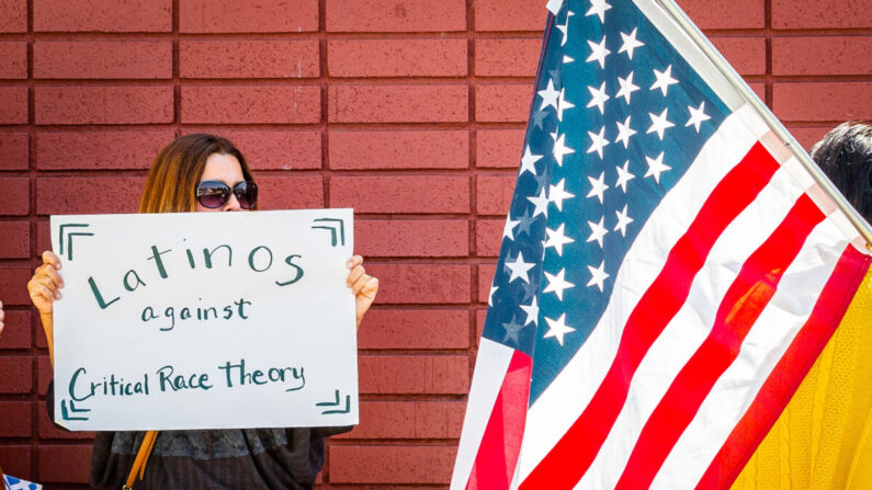 Una mujer sostiene un cartel contra la teoría crítica de la raza en Los Alamitos, California, el 11 de mayo de 2021. (John Fredricks/The Epoch Times)