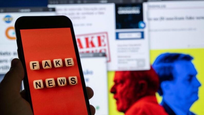 Esta imagen ilustrativa muestra la pantalla de un teléfono inteligente que muestra la frase "Fake News" delante de una pantalla de escritorio mostrando varias noticias, Río de Janeiro, Brasil, el 29 de agosto de 2022. (MAURO PIMENTEL/AFP vía Getty Images)
