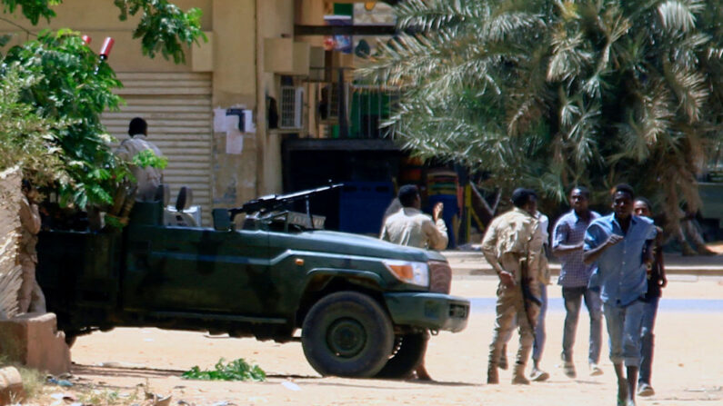 Varias personas pasan junto a un vehículo militar en Jartum (Sudán) el 15 de abril de 2023, en medio de los enfrentamientos registrados en la ciudad. (AFP vía Getty Images)