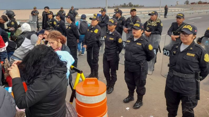Policías peruanos impiden la entrada a Perú de migrantes de varias nacionalidades que permanecen varados en la tierra de nadie en la frontera entre Perú y Chile, cerca de la ciudad de Tacna, en el sur de Perú, el 26 de abril de 2023. (Foto de JAVIER RUMICHE/AFP vía Getty Images)
