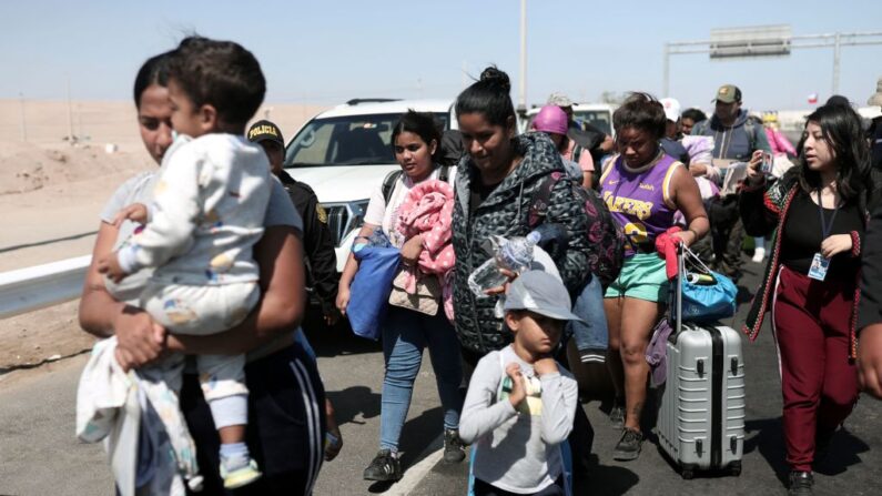 Migrantes de diferentes nacionalidades son escoltados por policías peruanos hasta una oficina de migración en Tacna, en la frontera entre Perú y Chile, el 28 de abril de 2023. (Aldair Mejia/AFP vía Getty Images)