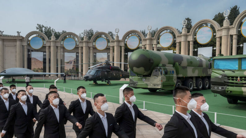 El 12 de octubre de 2022, en Beijing (China), varios guardias pasan junto a una muestra de material militar en una exposición sobre los años de liderazgo del presidente chino, Xi Jinping, en el marco del próximo XX Congreso del Partido. (Kevin Frayer/Getty Images)
