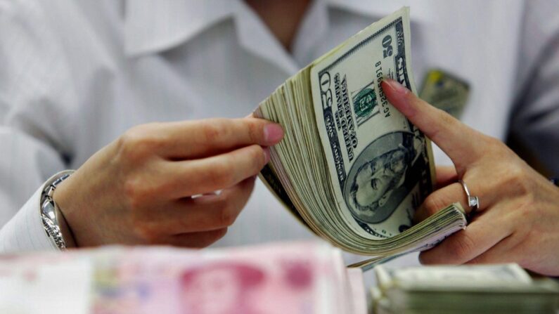 Un cajero cuenta la fajilla de yuanes chinos y dólares estadounidenses en un banco de Shanghái, China, el 22 de julio de 2005. (STR/AFP/Getty Images)
