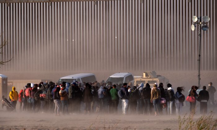 Inmigrantes ilegales esperan a ser procesados por agentes fronterizos estadounidenses en la frontera entre Estados Unidos y México, el 30 de marzo de 2023. (Guillermo Arias/AFP vía Getty Images)