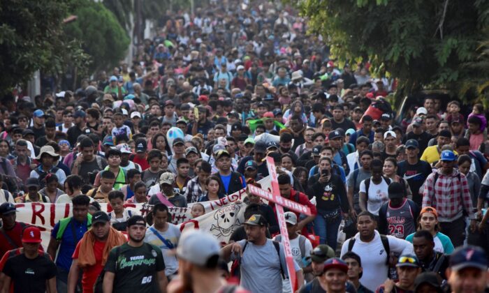 Migrantes de Centro y Sudamérica participan en una caravana que se dirige hacia la frontera entre México y Estados Unidos, mientras portan pancartas en protesta por la muerte de 40 migrantes en un incendio en un centro de detención mexicano, en Tapachula, México, el 23 de abril de 2023. (AFP vía Getty Images)