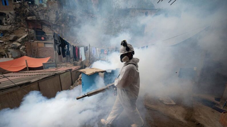 Un miembro de una brigada de salud fumiga una calle contra el virus del dengue en una barriada en las colinas del distrito de San Juan de Lurigancho, Lima (Perú), el 11 de mayo de 2023. (Cris Bouroncle/AFP vía Getty Images)