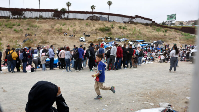 Inmigrantes que buscan entrar en Estados Unidos se reúnen en un campamento improvisado entre los muros fronterizos entre Estados Unidos y México el 12 de mayo de 2023 en San Diego, California. (Mario Tama/Getty Images)